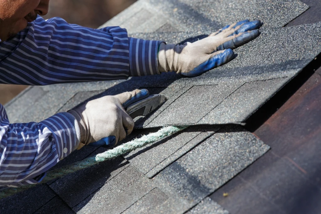 close up of roofing contractor working to install architectural shingles on roof