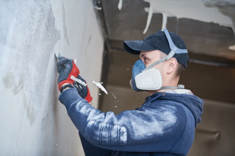 technician using protective apparel to clean walls after fire damage