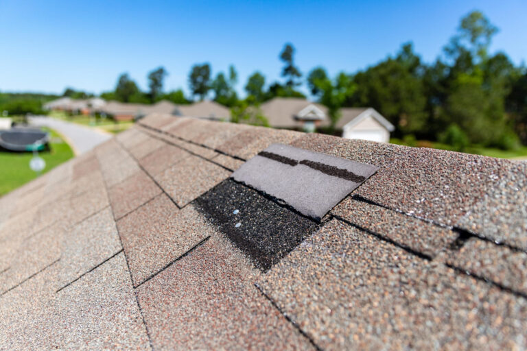 roof inspection before buying a house-close up of a lifted shingle near the peak of a roof
