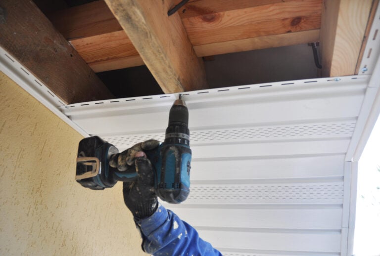 soffit repair-man using power drill to install new soffit materials