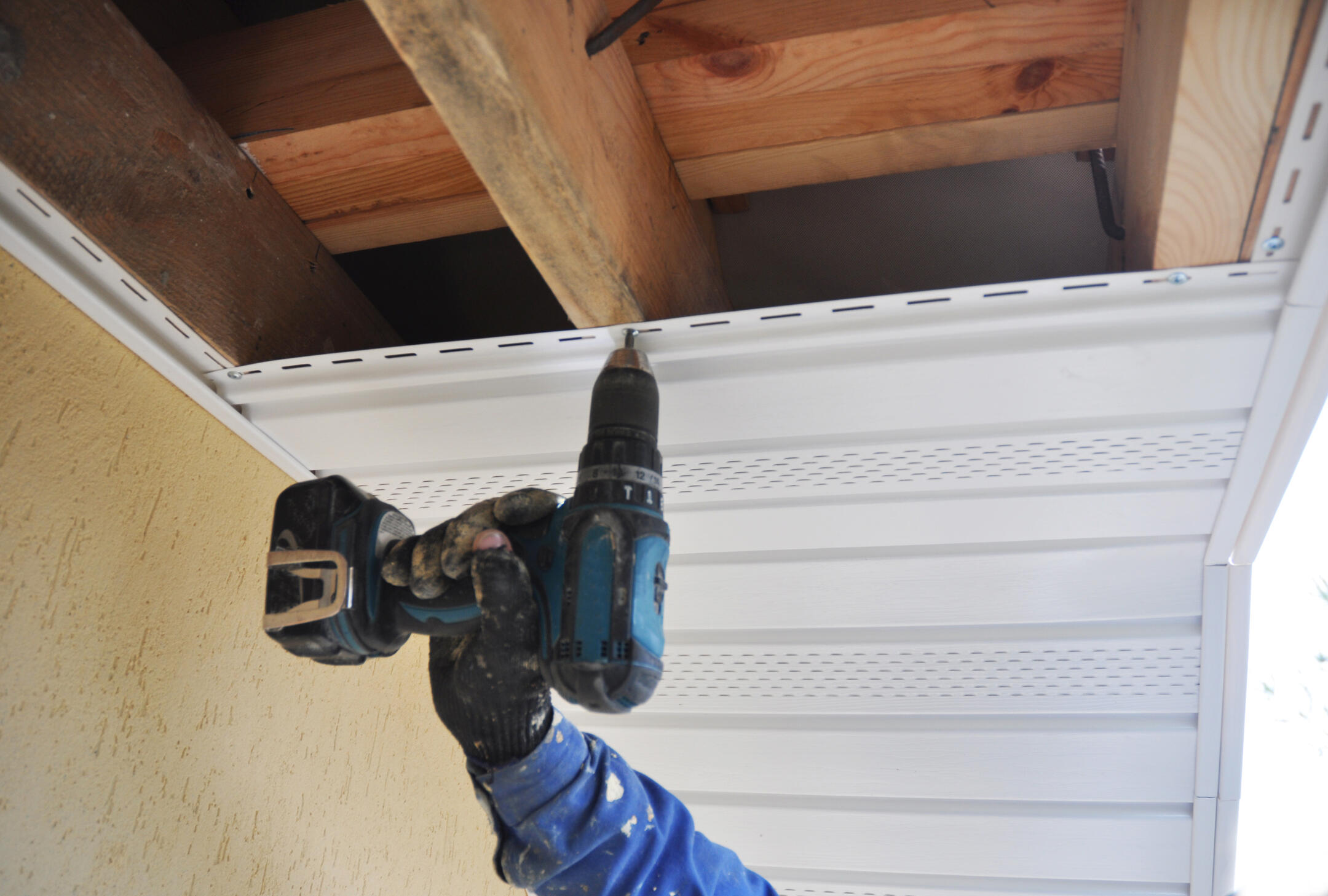 soffit repair-man using power drill to install new soffit materials