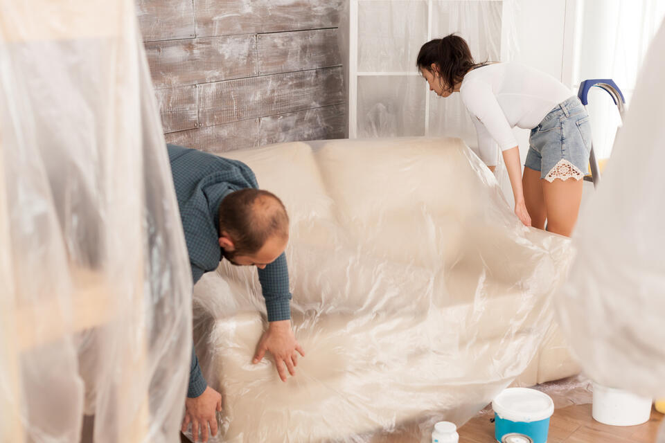 should i stay home during roof replacement-a couple covering their furnature with tarps to protect their items from debris during construction