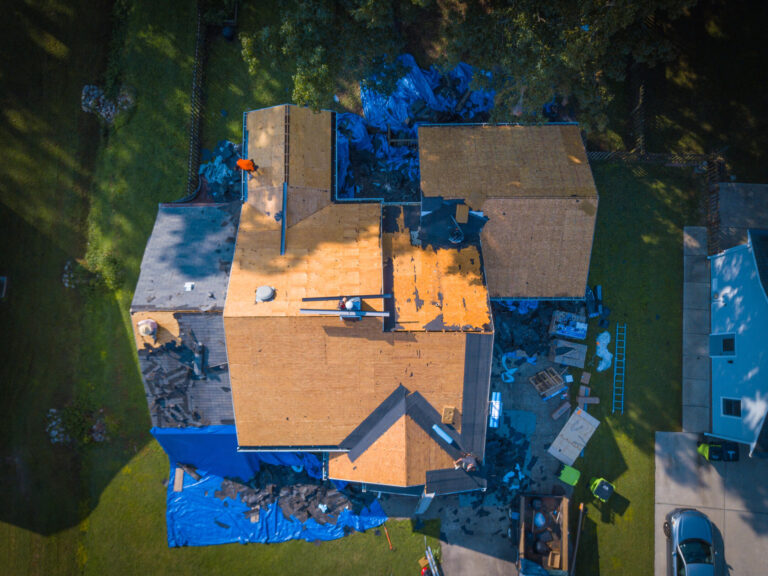 should i stay home during roof replacement-aerial view of a home getting a roof replacement with debris and materials all over yard