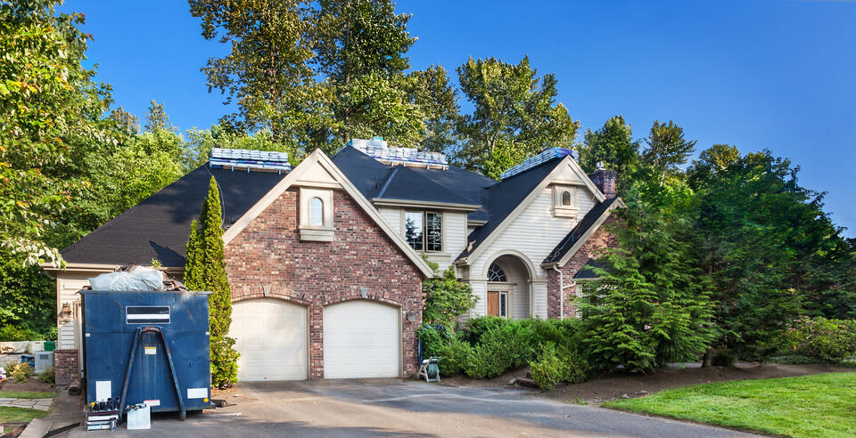 should i stay home during roof replacement-brick home with construction materials on roof, in yard, and on driveway