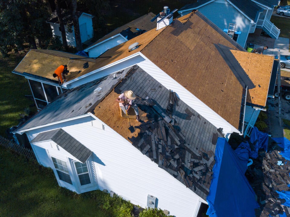 should i stay home during roof replacement-roofing crew removing old roofing materials from a home